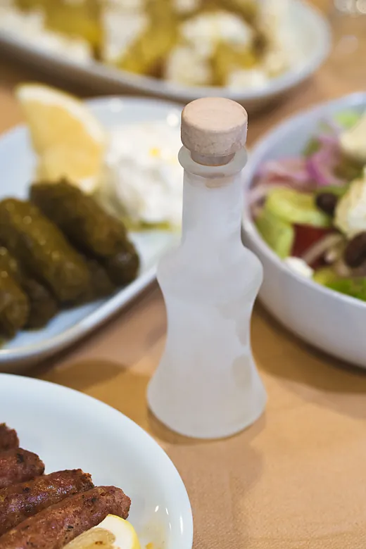 Μπουκάλι ρακί ανάμεσα στα πιάτα